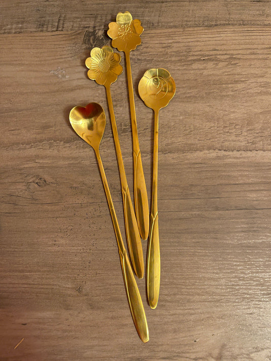 Gold teaspoons shaped: daisy, heart, rose, and cherry blossom.